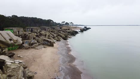 aerial view of abandoned seaside fortification building at karosta northern forts on the beach of baltic sea in liepaja in overcast spring day, wide drone shot moving backwards