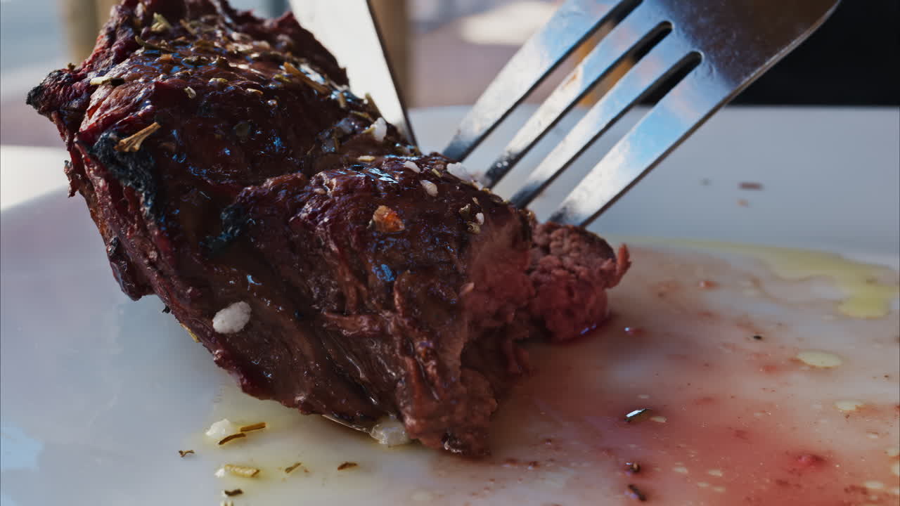 Close up of stake being cut near with fries and salad on a white plate