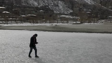 Aerial-Circle-Dolly-Around-Adult-Male-Walking-Across-Frozen-Khalti-Lake