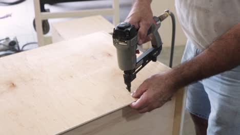 man nailing cabinet pieces together