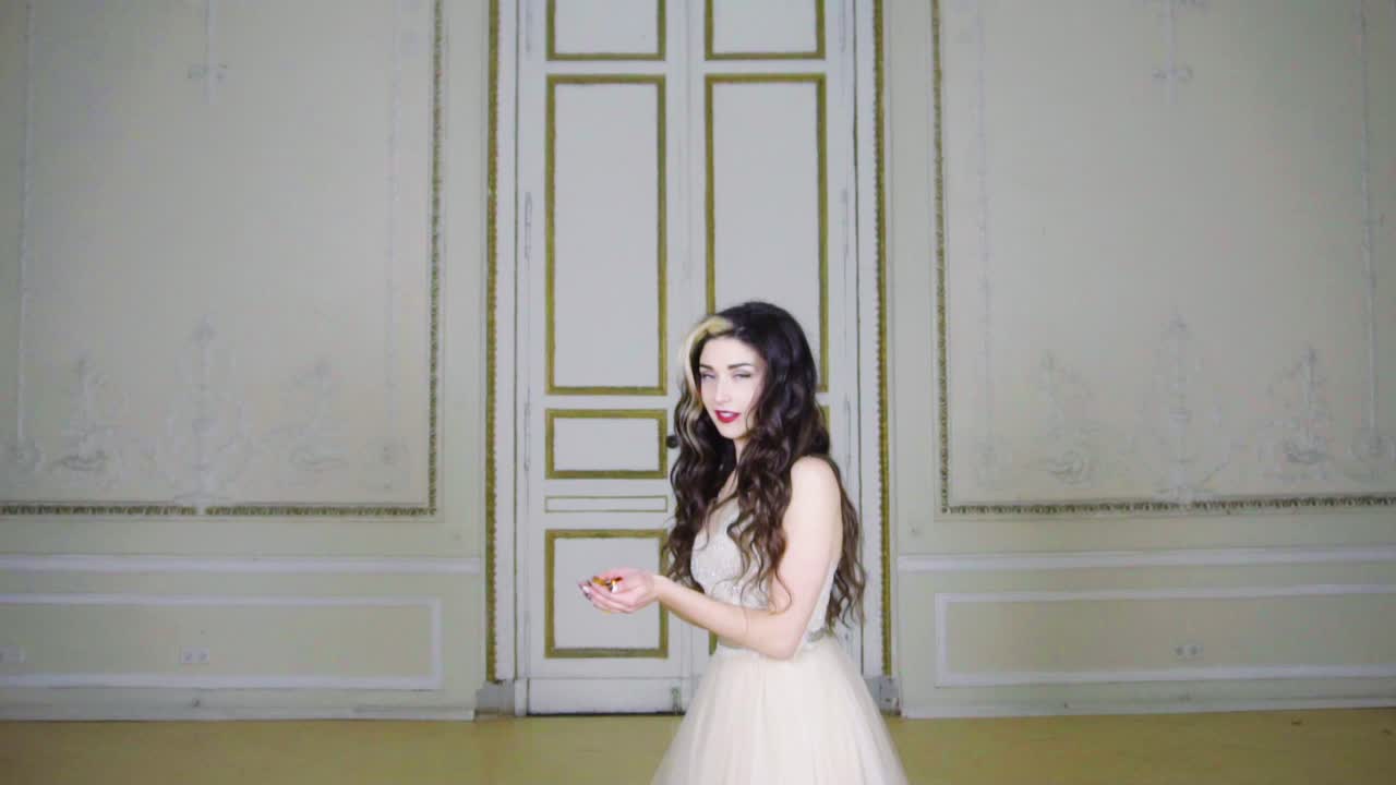 빨간 입술을 가진 젊은 갈색 머리 여자가 금 색종이를 불다