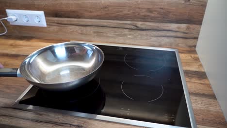 woman putting a frying pan on an electric hot plate