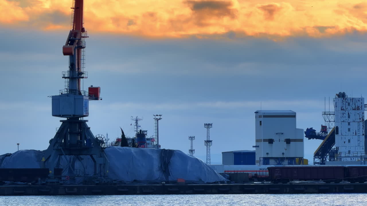 Burgas, Bulgaria, 29 October 2025: Large crane at port with cargo and colorful sunset in the background. A crane stands at the port, lifting cargo as the sun sets, casting colors in the sky