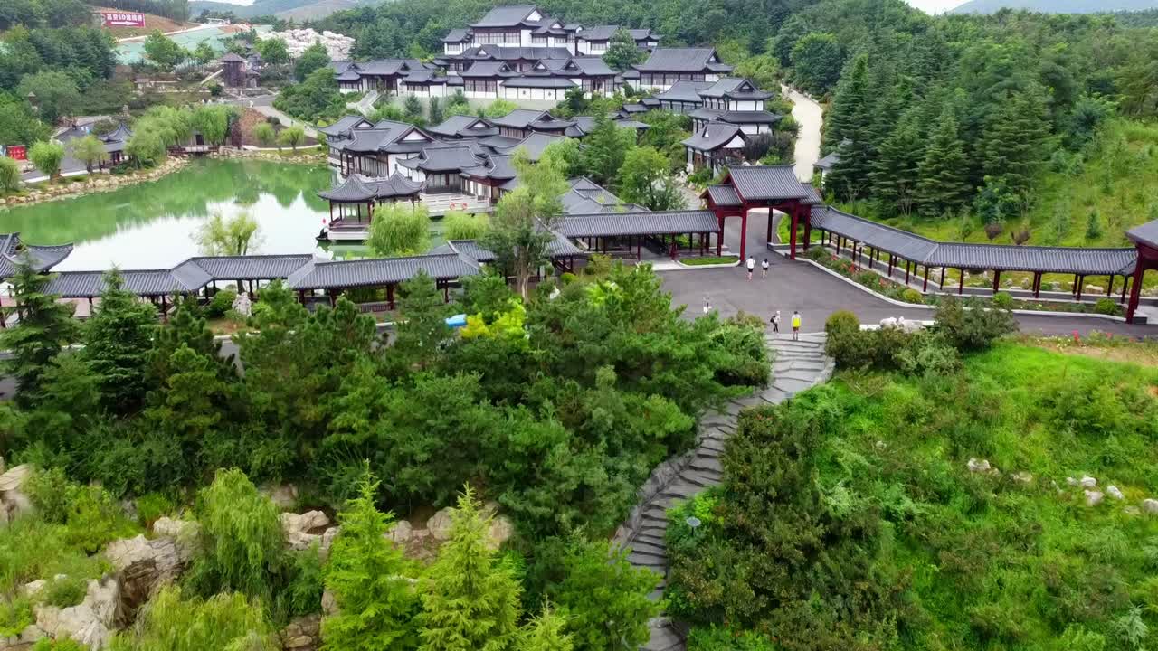 tour aéreo del parque huaxiacheng con edificios tradicionales y lago en weihai, china