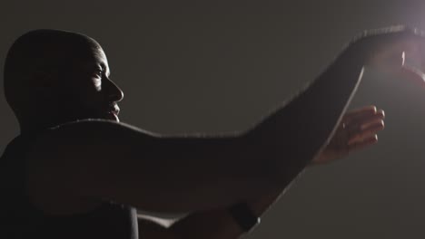 close up side view studio shot of male basketball player shooting ball at basket