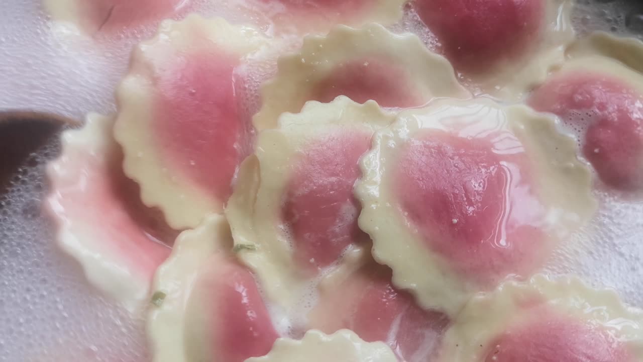 Colourful Fiorelli beetroot and goat cheese pasta close up stirring bubbling in hot boiling pan of water