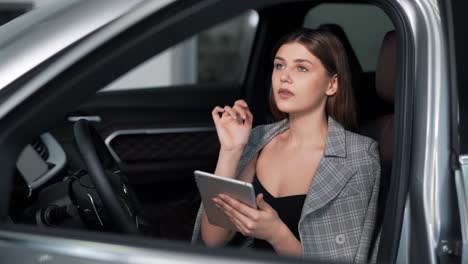 Stilvolles-Erwachsenes-Mädchen-In-Einem-Business-Anzug-Mit-Einem-Tablet-Im-Auto