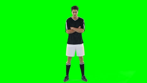 confident football player standing against green screen