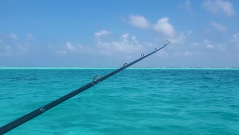 man's hand holding a fishing rod while standing on a sailing boat caribbean sea