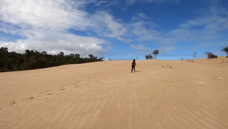 a young boy runs off into the distance on large coastal dunes
