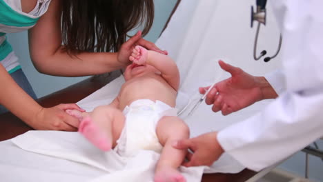 madre y doctora haciendo una inyección a un bebé que llora
