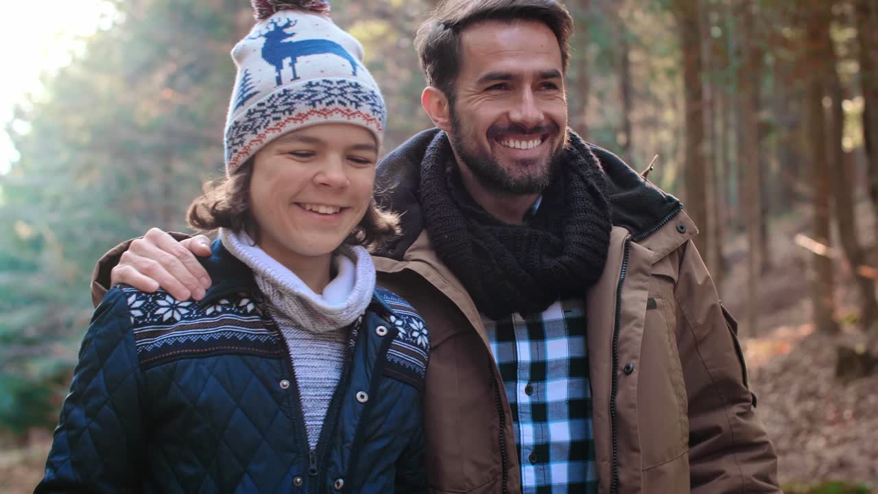 Papà felice e figlio adolescente che camminano nella foresta autunnale