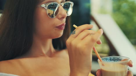 young-girl-is-sunbathing-by-the-pool-and-sipping-a-drink-from-a-straw