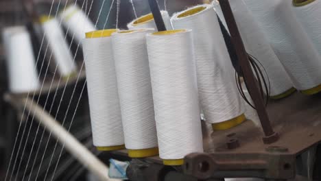 close-up of textile machinery with spools of white thread