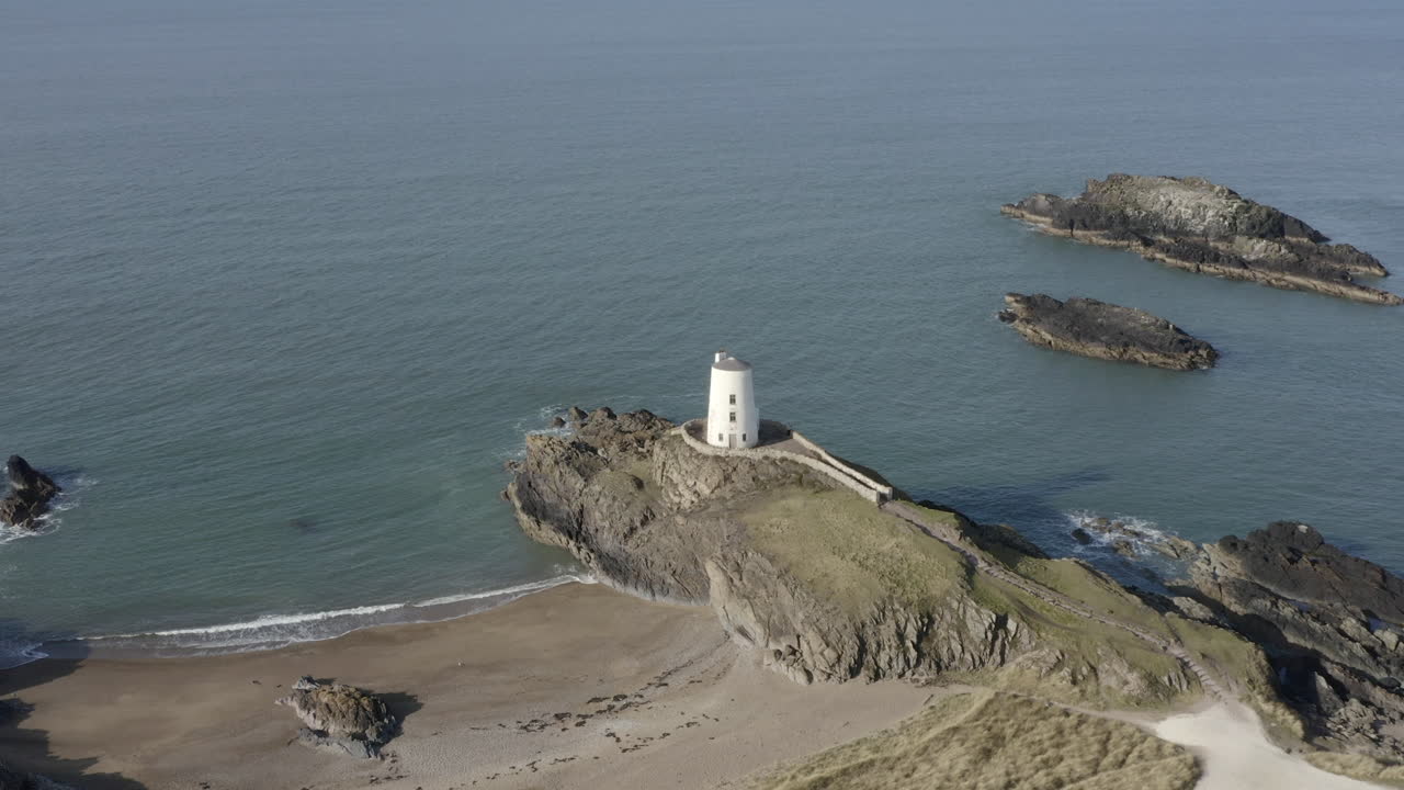 una vista aérea del faro de twr mawr en la isla de ynys llanddwyn, volando de derecha a izquierda alrededor del faro, anglesey, gales del norte, reino unido.