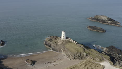 an aerial view of twr mawr lighthouse on ynys llanddwyn island, flying right to left around the lighthouse, anglesey, north wales, uk