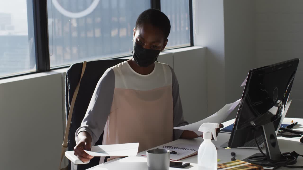 African american businesswoman wearing face mask, working in office