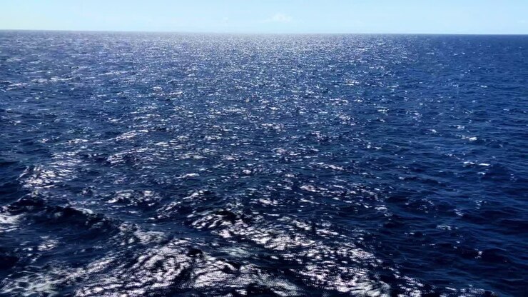 Ampia vista delle onde dell'oceano mentre il sole si riflette sulle acque spumeggianti che si muovono. Segmento 2 di 2