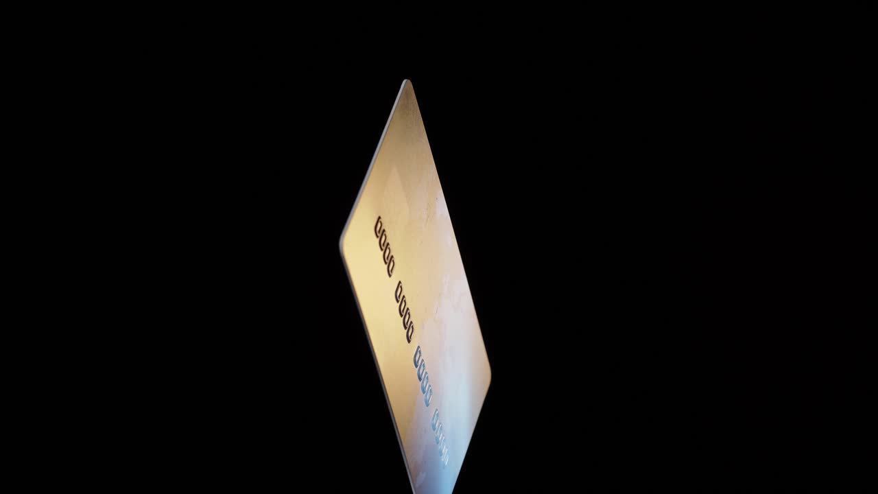 Credit plastic card turning spinning isolated on black background, online payment operations concept