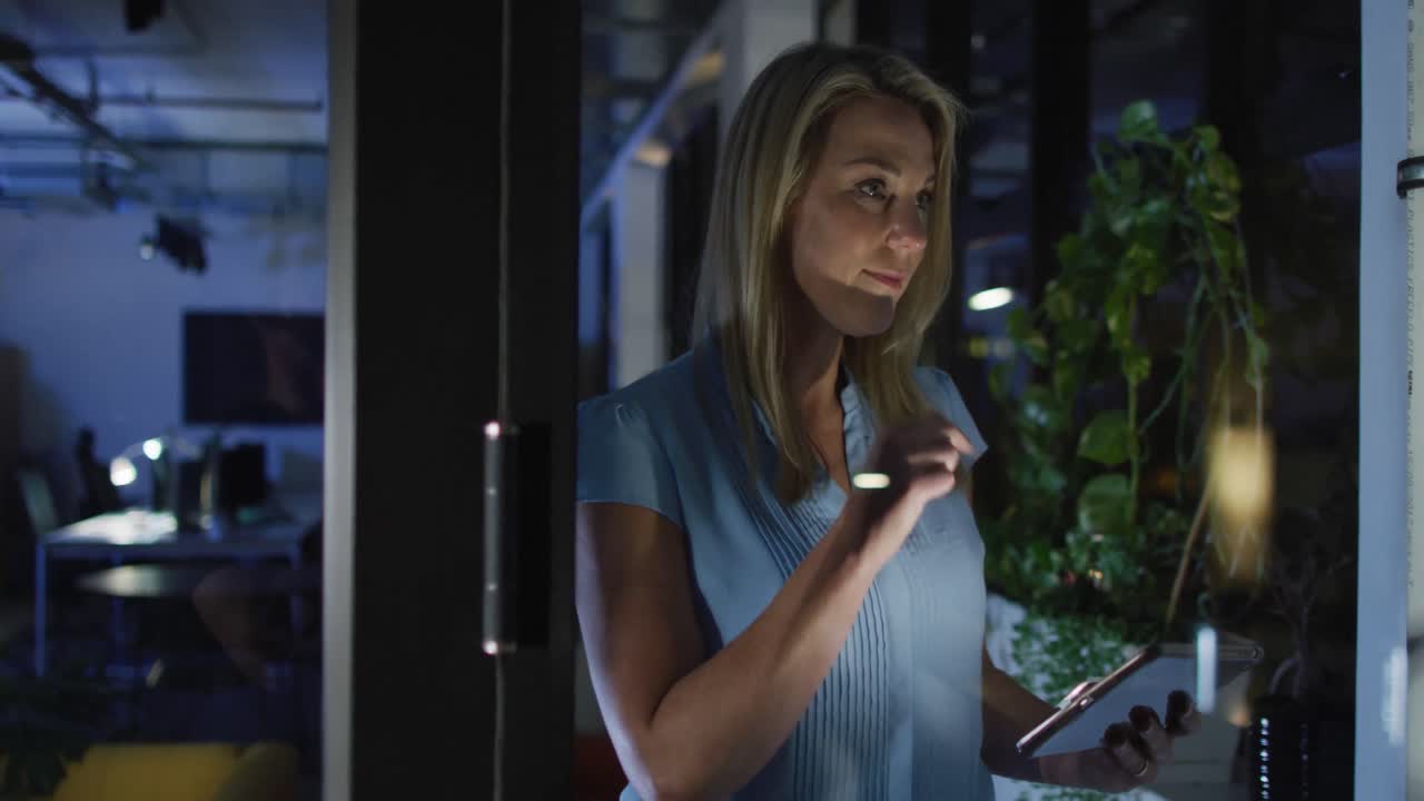 Video of caucasian woman with tablet working late in office