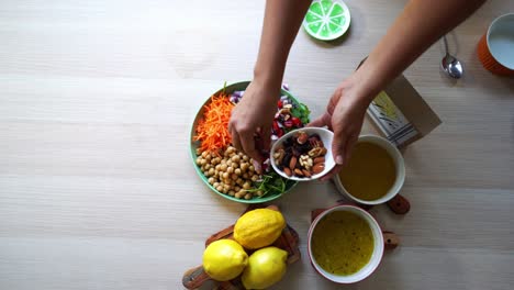 Adding-nuts-to-chick-pea-salad-aerial-view-of-making-a-salad-tomatoes-carrots-spinach-chick-peas-lemons-onions-nuts-dressing-in-view