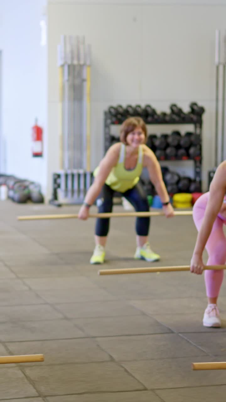 Mulheres se Exercitando com Barras em uma Aula de Fitness em Grupo