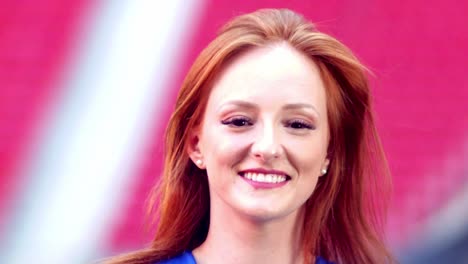 beautiful young red hair woman smiling with the stadium on the background