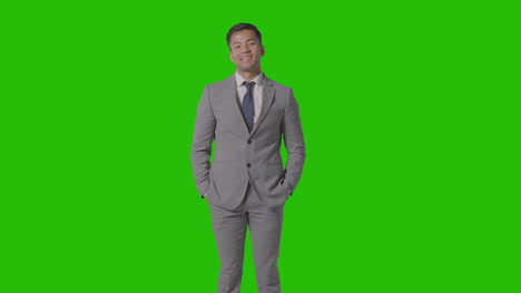 Three-Quarter-Length-Portrait-Of-Businessman-In-Suit-Against-Green-Screen-Smiling-At-Camera