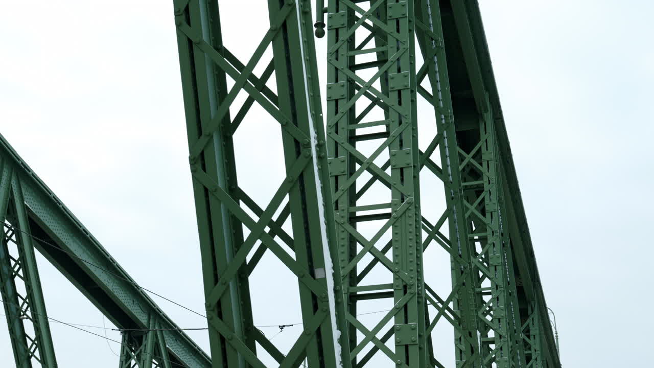 Close-up of the Liberty Bridge in Budapest during winter, highlighting historic iron architecture, green steel details, and cold seasonal atmosphere along the Danube