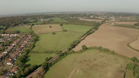 Aerial-shot-of-London-underground-train-heading-towards-Epping-town-under-the-M25-motorway