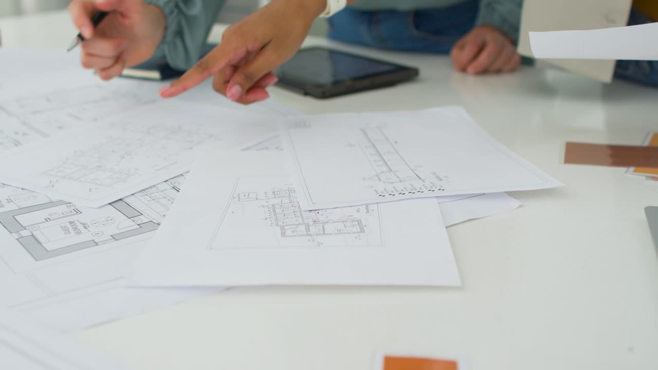 Colegas de trabalho diversas organizando e planejando à mesa com caneta, mão direita colocando folha