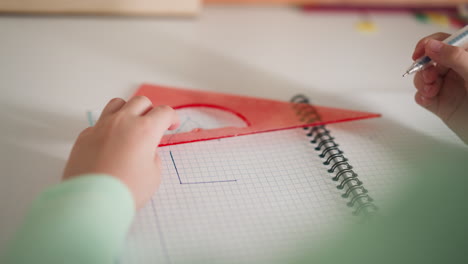 little student draws triangular shape with ruler and pen