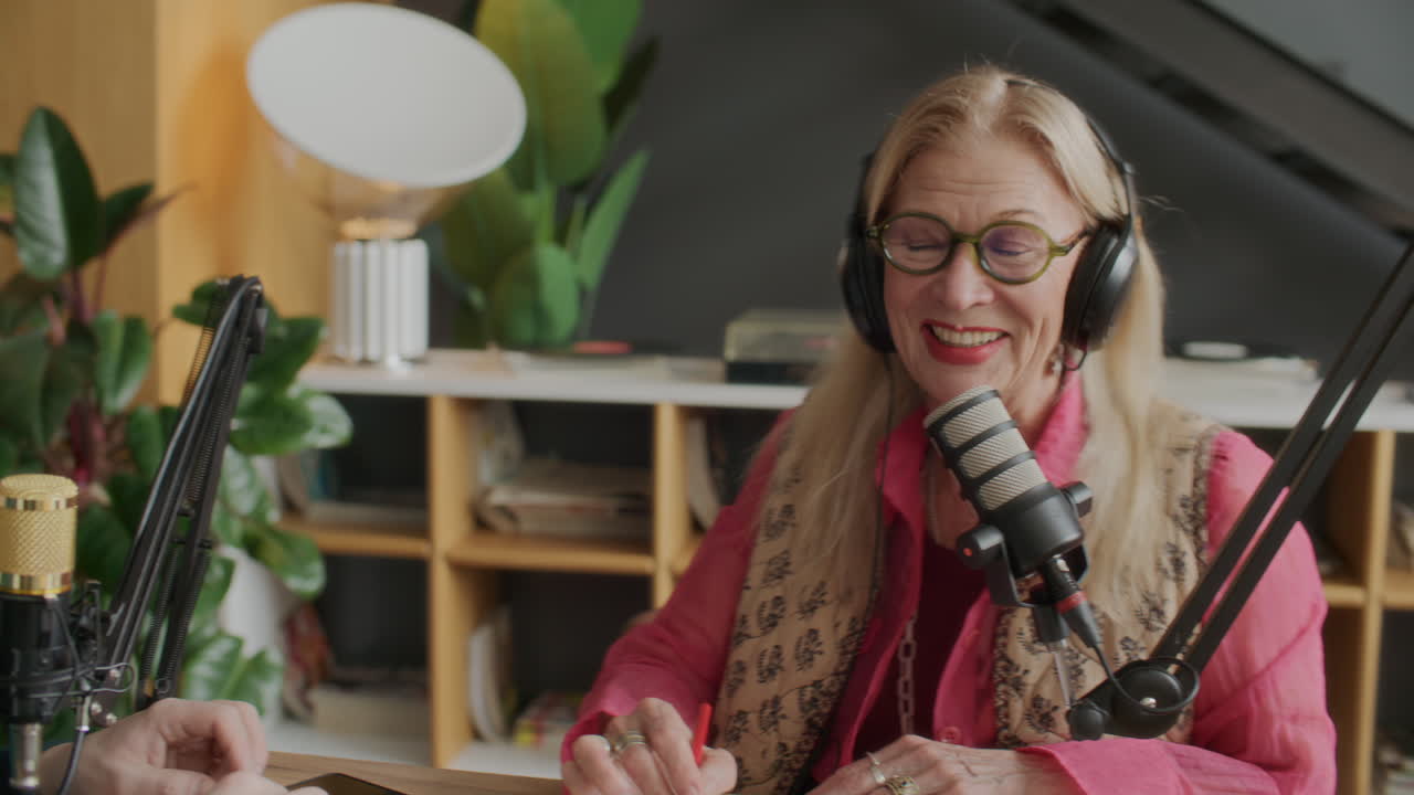 Elderly Female Podcaster Hosting Interview with Guests in Recording Studio