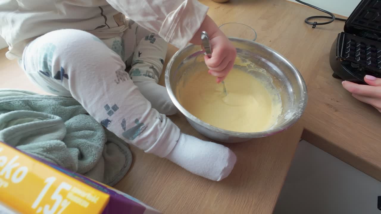 close-up shot of a kid mixing pancake dough on the kitchen table.