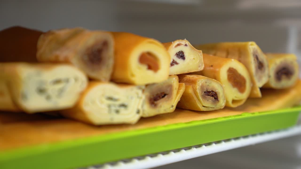 Vari involtini di formaggio salati ripieni di diversi ingredienti su un vassoio da portata verde brillante