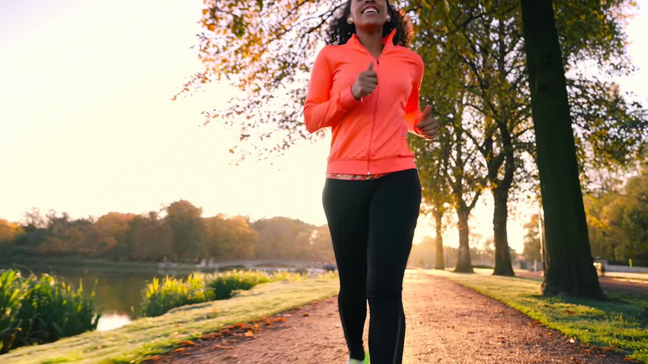 Video da un’angolazione dal basso di una donna che fa jogging in un parco, catturando il vivace scenario autunnale