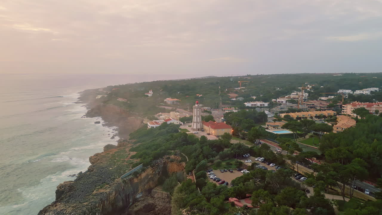 Dusky sky rough coast washed by powerful ocean aerial view. Modern lighthouse