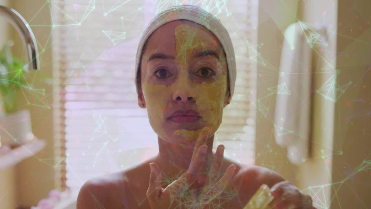 Woman dipping fingers, applying yellow mask for beauty, smoothing, network overlay drifting on face
