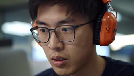 focused on the task: a young man engaged in deep concentration while wearing headphones in a modern workspace, highlighting the importance of sound in productivity