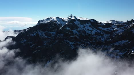 dron shot backwards with thin clouds around the mountain pico ruivo in madeira