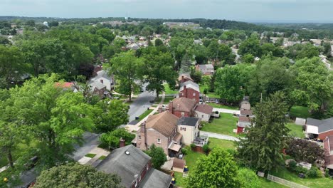 quiet middle class residential area in american suburb. green trees and green lush grass in garden of homes. sunny day in summer. aerial flyover shot