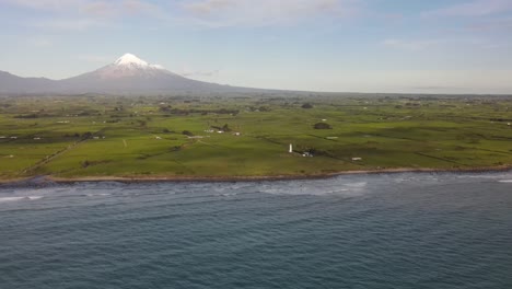 aerial scenic of new zealand coastal landmark with lighthouse, iconic taranaki volcano on backdrop