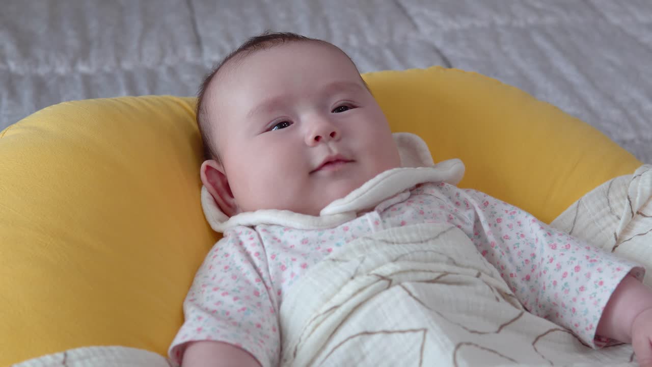 침실에 쿠션에 등을 대고 누워 있는 유라시아 아기 소녀