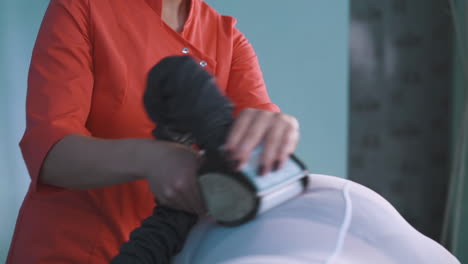 beautician in orange shirt does roller massage to plump lady