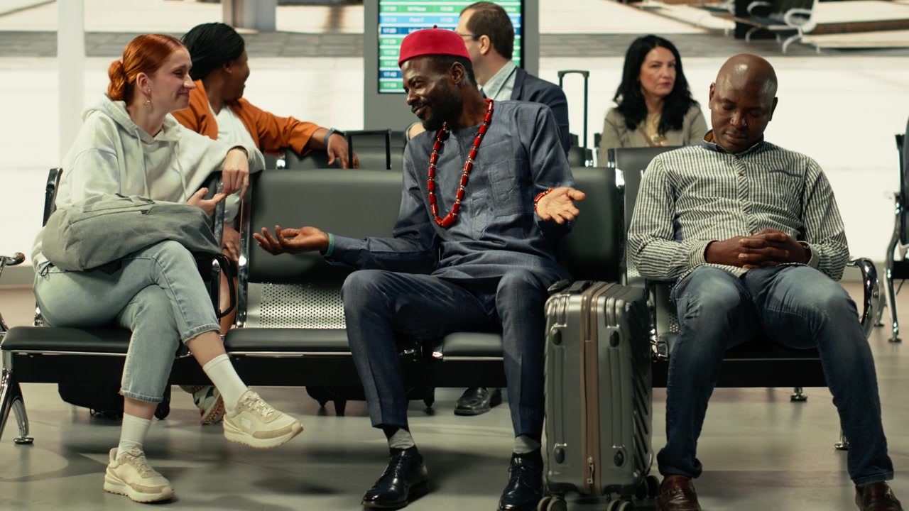 Man in traditional African clothing and woman waiting at bus station