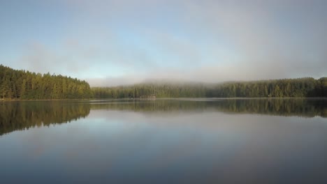 Nebelwolke-über-Bäumen-Um-Seewasser-Mit-Spiegelung-Am-Morgen