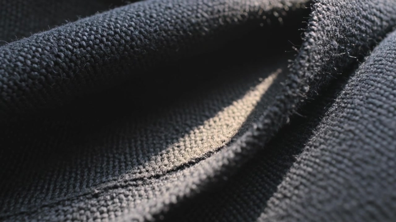 Gros plan sur un tissu tricoté foncé plié, le focus changeant, révélant la texture des peluches de couture.