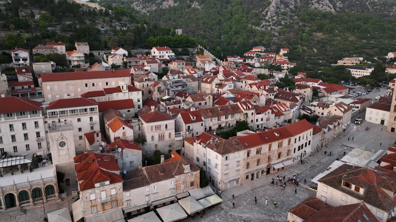 Aerial arc shot flying over the town of Hvar, Croatia towards the mountains on a clear day.