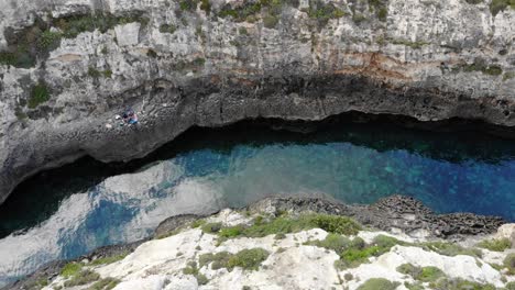 View-down-to-river-from-rocky-cliffs-reflecting-clouds-in-Gozo,-Ghasri,-Malta-island