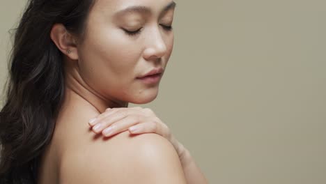 asian woman with dark hair on beige background with copy space, slow motion